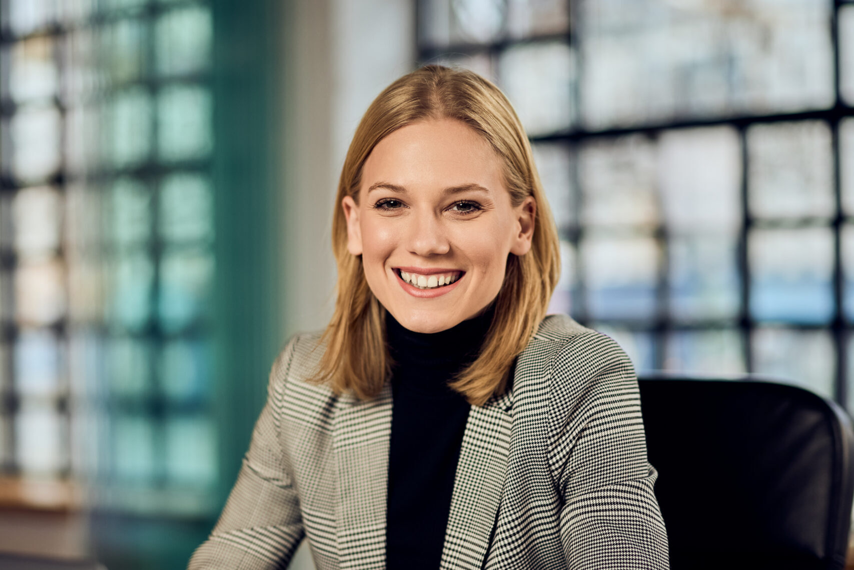 confident businesswoman smiling at office desk with laptop on modern workspace